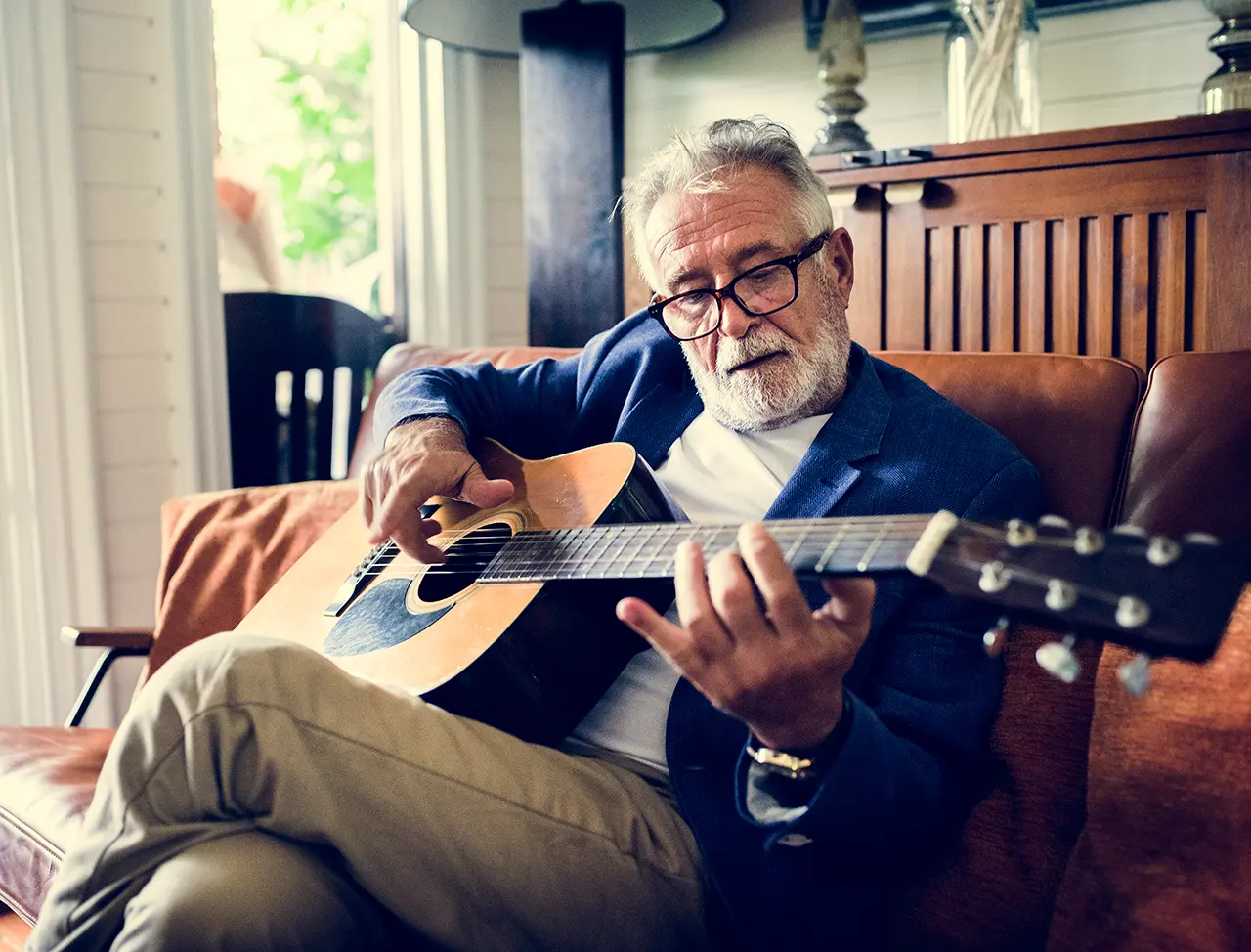 An elderly man playing a guitar